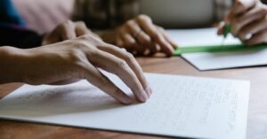 Hands feel Braille text on paper, demonstrating tactile reading and sensory education.